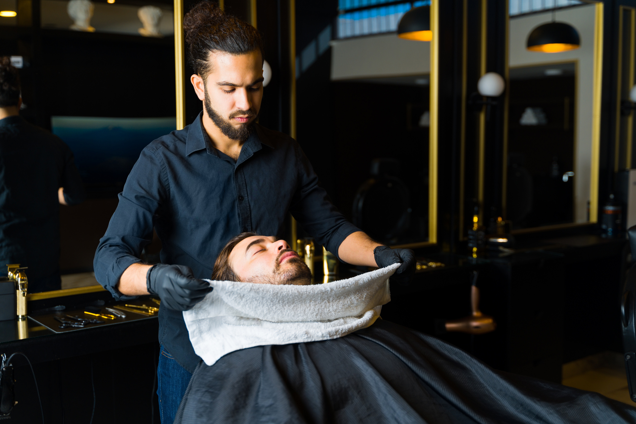 Hispanic barber using a hot towel before shaving